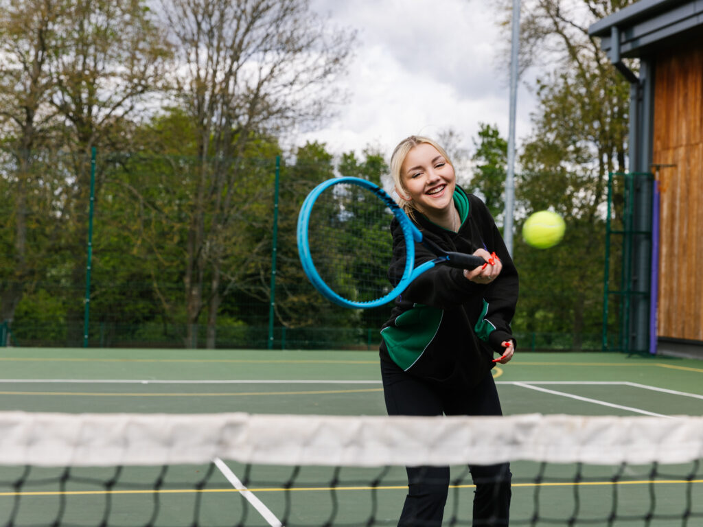 student hitting a tennis ball